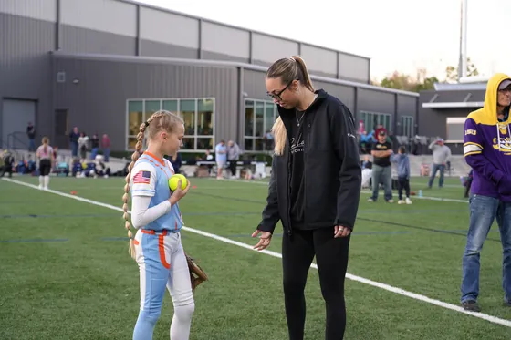 Montana Fouts holding a softball with an athlete